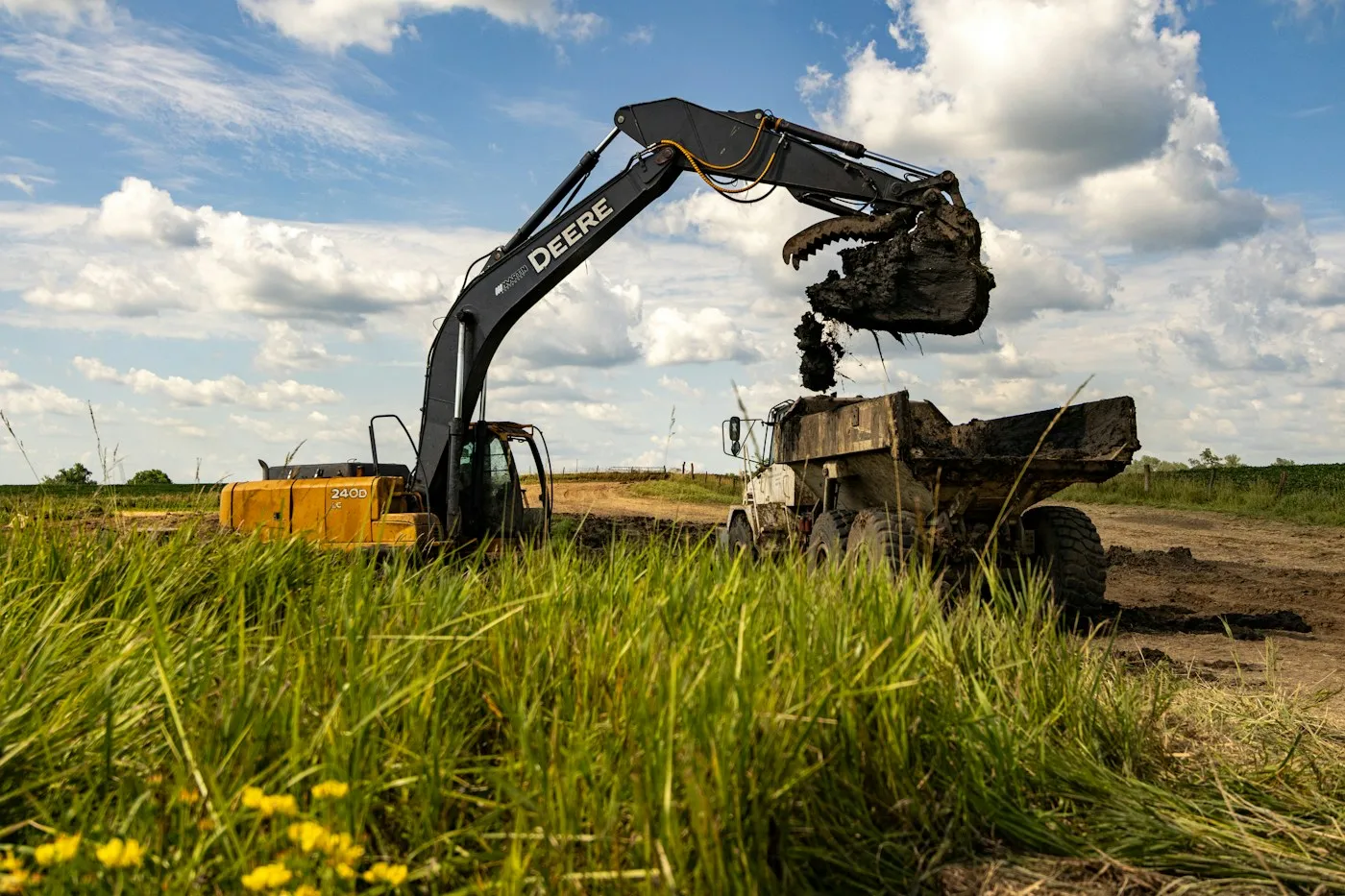 Excavator working beside grass and soil