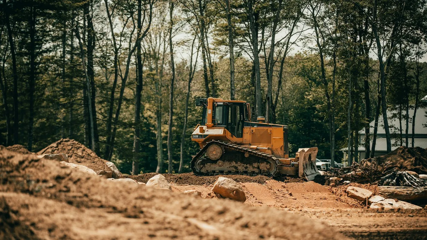 Wide view of a bulldozer and exposed earth in woodland